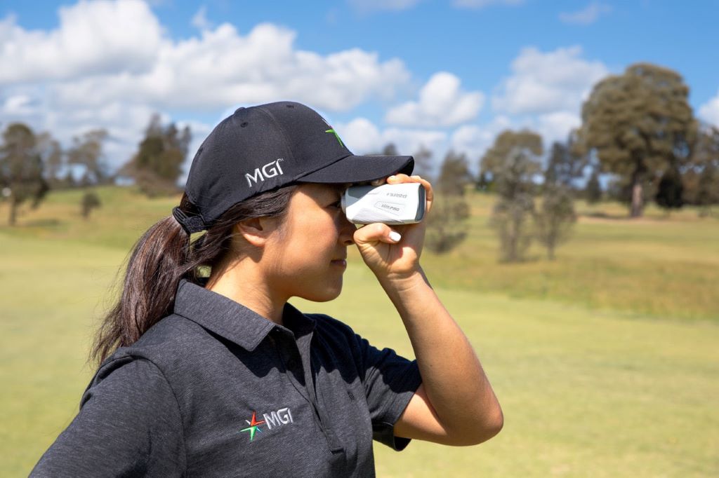 Golfer using a rangefinder to measure distance before selecting a club
